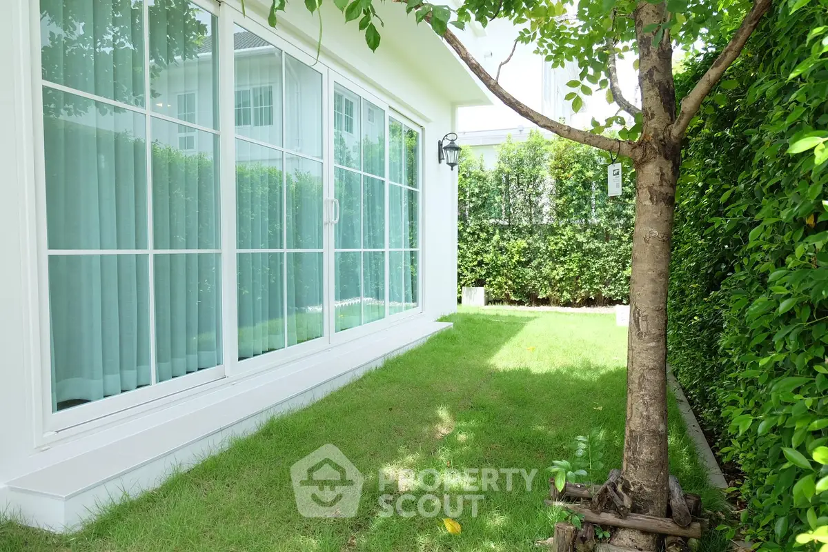 Charming garden view with lush greenery and modern sliding glass doors in a serene residential setting.