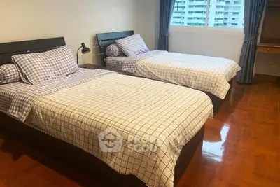 Spacious bedroom with twin beds and large window offering city view