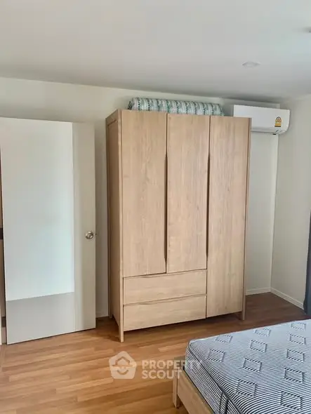 Modern bedroom with wooden wardrobe and air conditioning unit, featuring a comfortable bed and stylish decor.