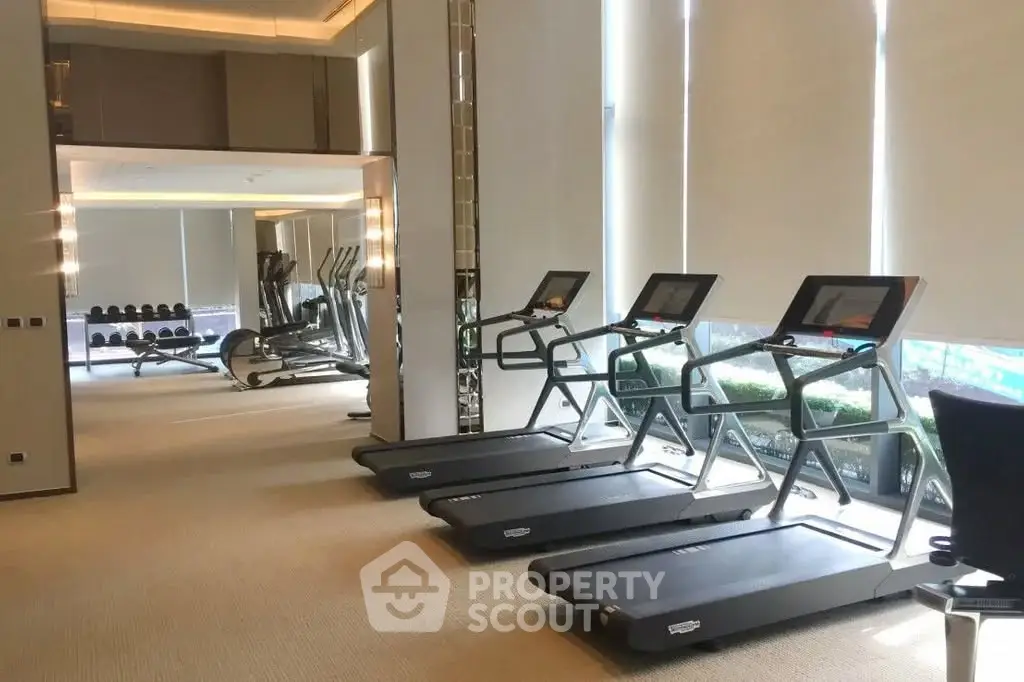 Luxurious gym with modern treadmills and fitness equipment in upscale residential building.