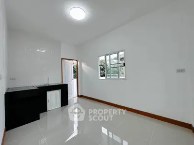 Bright kitchen with sleek black countertop and white cabinets, featuring a window view.