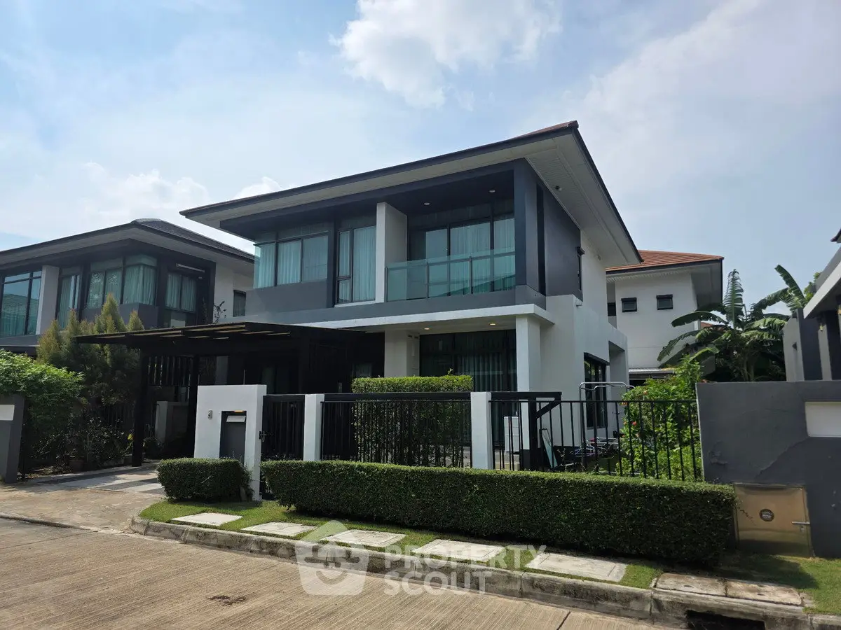 Modern two-story house with sleek design and lush greenery in a serene neighborhood.
