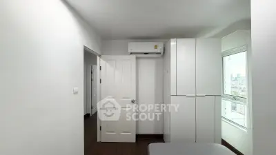 Modern bedroom with sleek white wardrobe and air conditioning, offering a bright and airy atmosphere.