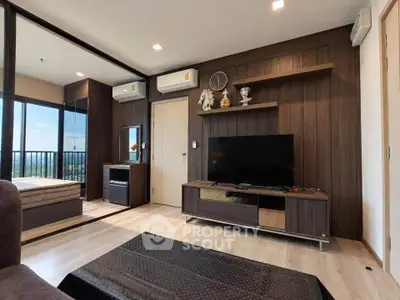 Modern living room with stylish decor and large TV, featuring a cozy bedroom view.