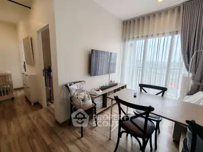 Modern living room with wooden flooring, wall-mounted TV, and dining area with natural light.