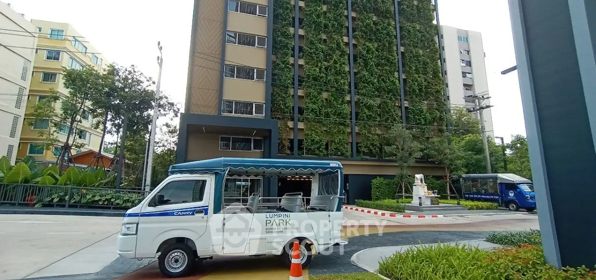 Modern residential building with lush vertical garden and shuttle service in urban setting.