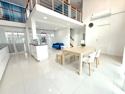 Spacious modern living area with open kitchen and dining space, featuring sleek design and abundant natural light.