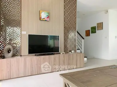 Modern living room with stylish decor and flat-screen TV, featuring elegant wood paneling and artistic accents.