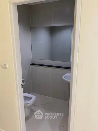 Compact bathroom with modern tiles and sleek fixtures, perfect for efficient space utilization.