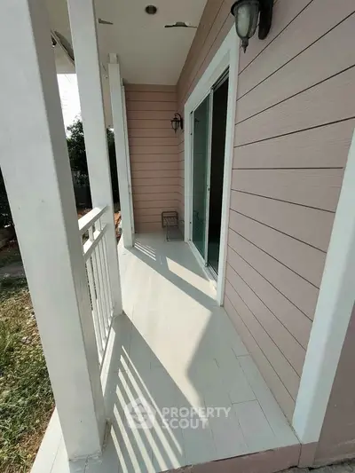 Charming small balcony with white railing and pink siding, perfect for relaxing outdoors.