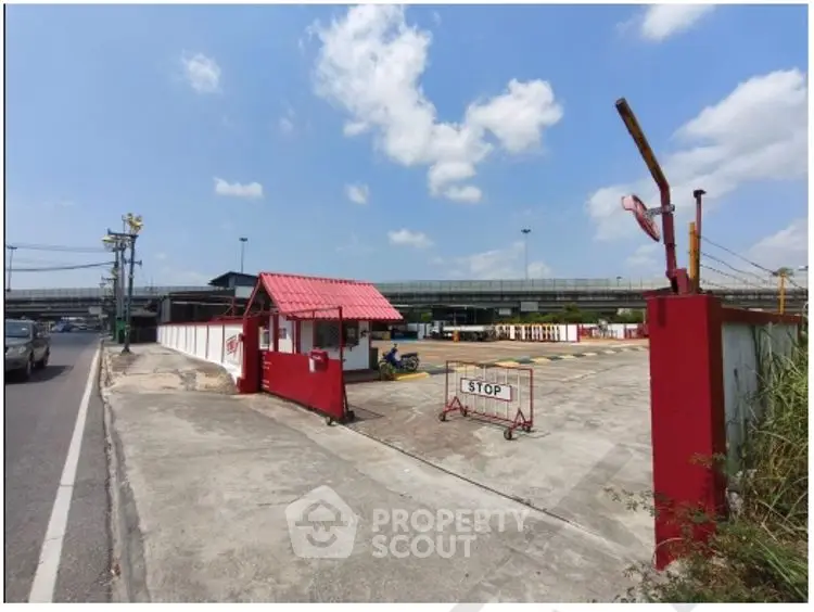 Secure gated entrance to commercial parking lot with clear sky and road access.