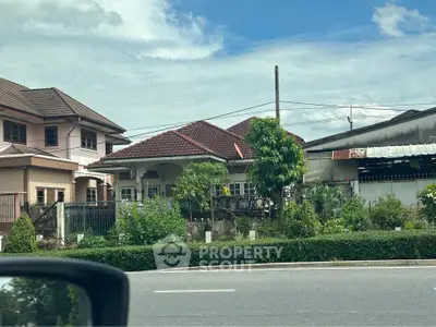 Charming suburban house with lush garden and tiled roof under a clear blue sky.