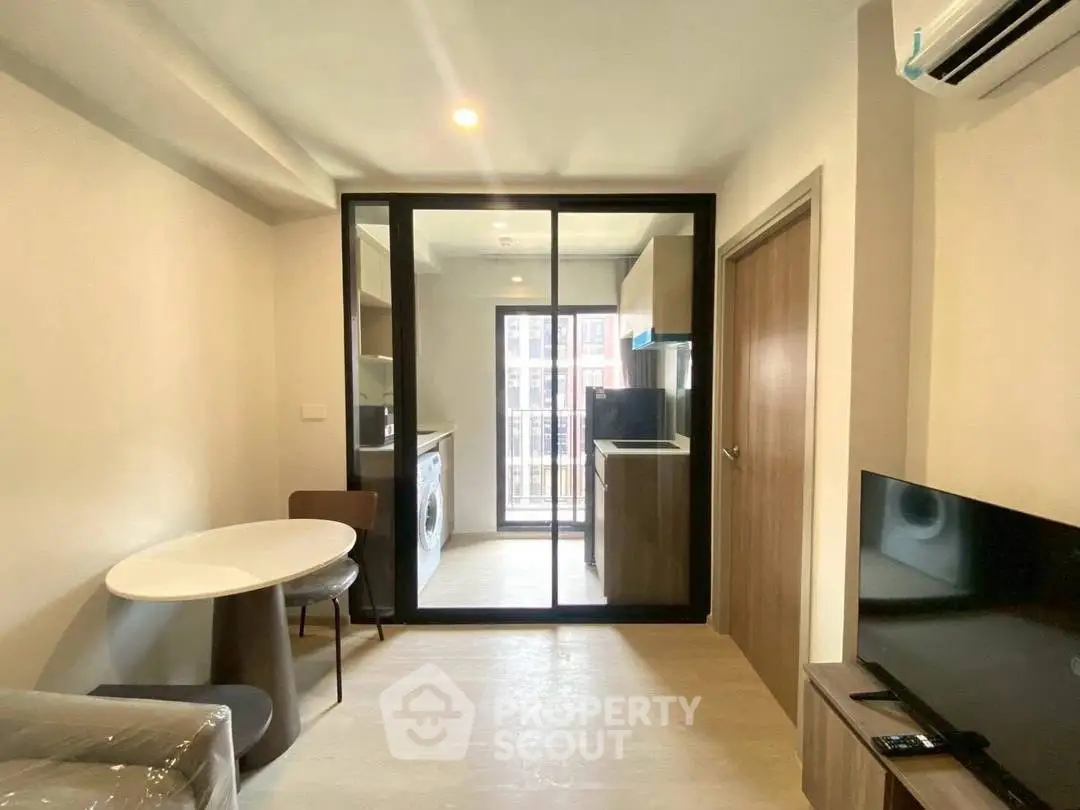Modern apartment interior with open kitchen and living area, featuring sleek furniture and natural light.