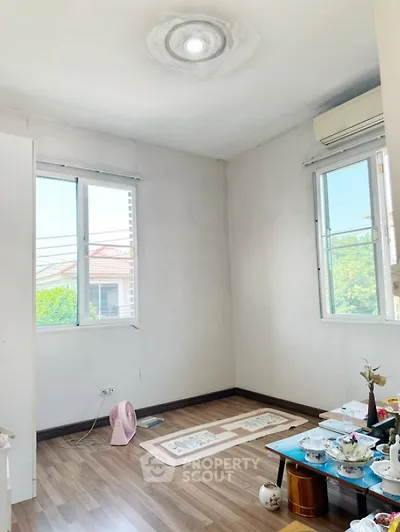 Bright room with wooden flooring and large windows, ideal for cozy living space.
