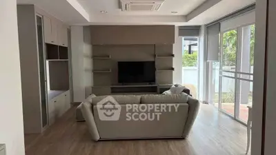 Modern living room with sleek furniture and large windows offering natural light.