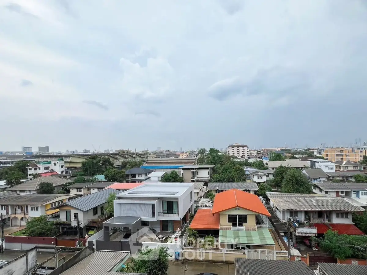 Panoramic view of suburban neighborhood with diverse rooftops and cloudy sky.