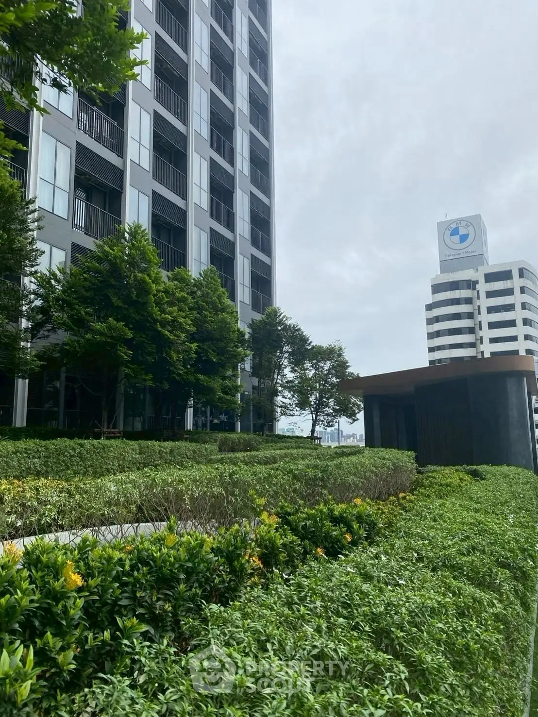 Modern high-rise building with lush green landscaping and city view.