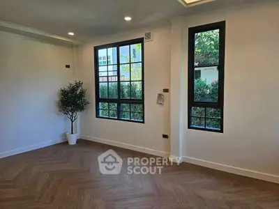 Spacious living room with large windows and elegant wooden flooring