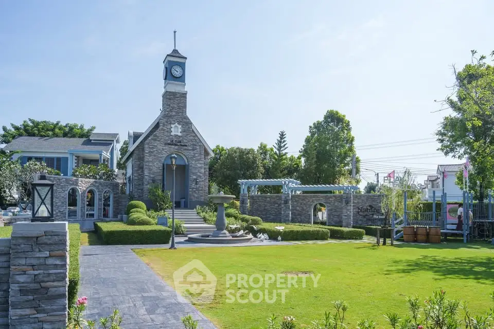 Charming stone building with clock tower in lush garden setting, perfect for serene living.