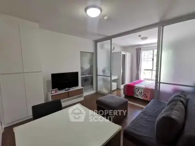 Modern studio apartment with open layout, featuring a cozy living area and bedroom separated by glass partitions.