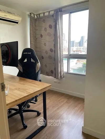 Modern study room with large window and wooden desk in urban apartment.