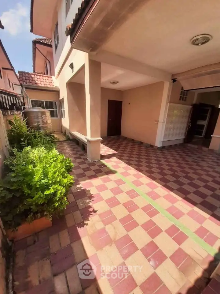 Charming exterior view of a spacious home with tiled patio and lush greenery.