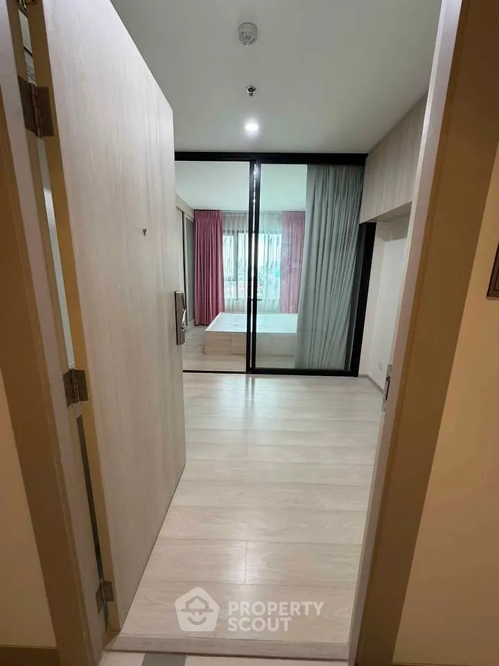 Modern apartment entrance leading to a stylish bedroom with large windows and elegant curtains.