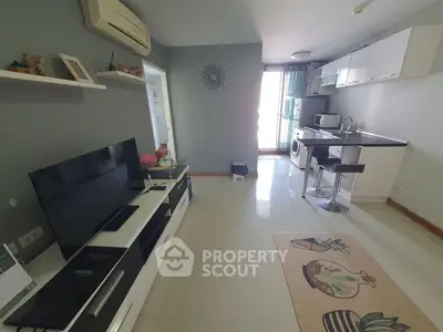 Modern living room with open kitchen, featuring sleek furniture and appliances, ideal for urban living.