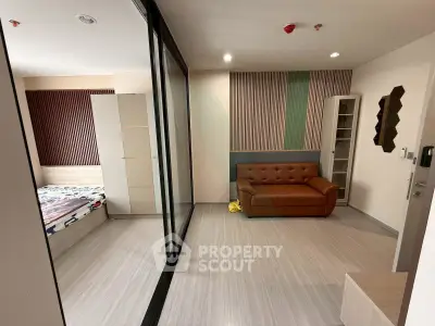Modern apartment interior with stylish living room and cozy bedroom separated by glass partition.