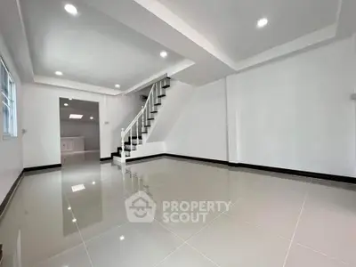 Spacious modern living room with sleek tile flooring and staircase, perfect for contemporary living.