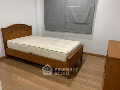 Cozy bedroom with wooden bed frame and mattress, featuring elegant wood flooring and neutral decor.