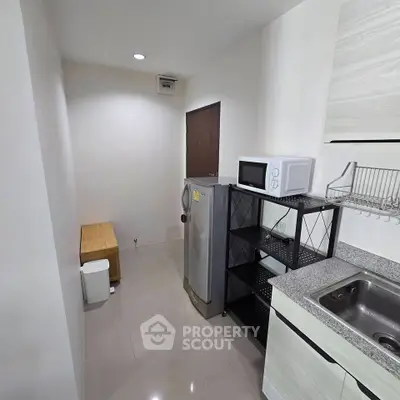 Compact kitchen with modern appliances and sleek design, featuring a microwave and refrigerator.