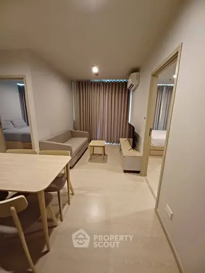 Modern living room with dining area in a cozy apartment, featuring neutral tones and minimalist furniture.