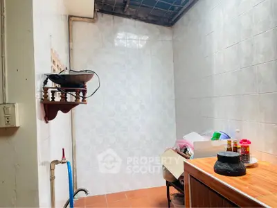 Compact kitchen space with tiled walls and basic amenities.