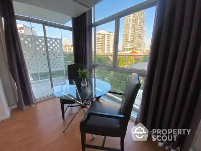 Modern apartment with glass table and city view from large windows.