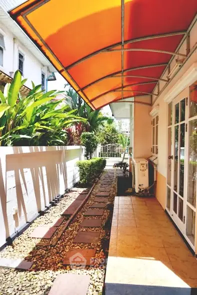 Charming garden pathway with vibrant orange awning and lush greenery