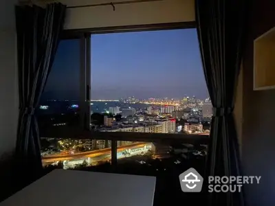 High-rise city view from a cozy room with large windows, showcasing a stunning night skyline and urban lights, perfect for urban living.