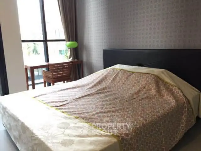 Cozy bedroom with modern decor and large window for natural light.