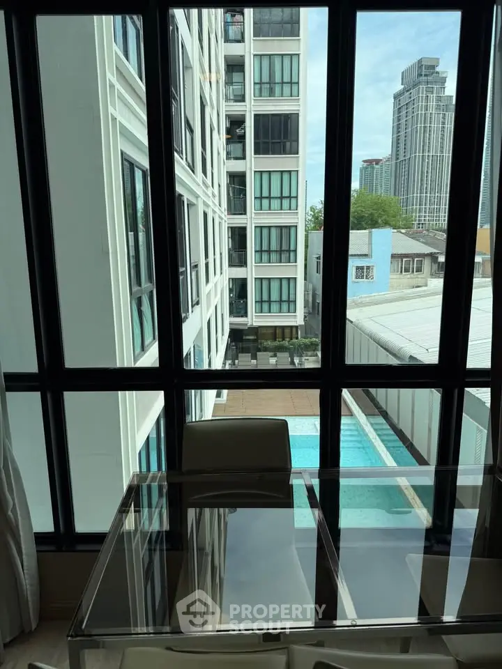 Modern apartment with pool view and floor-to-ceiling windows, offering a bright and airy living space.