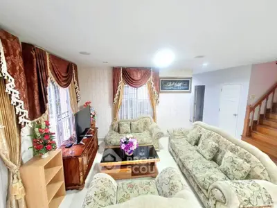 Elegant living room with plush sofas and floral curtains in a cozy home setting.