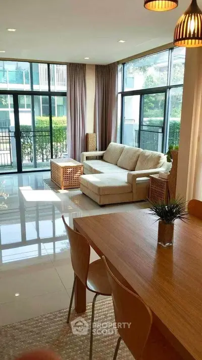 Spacious living room with large windows and modern furniture, offering a bright and inviting atmosphere.