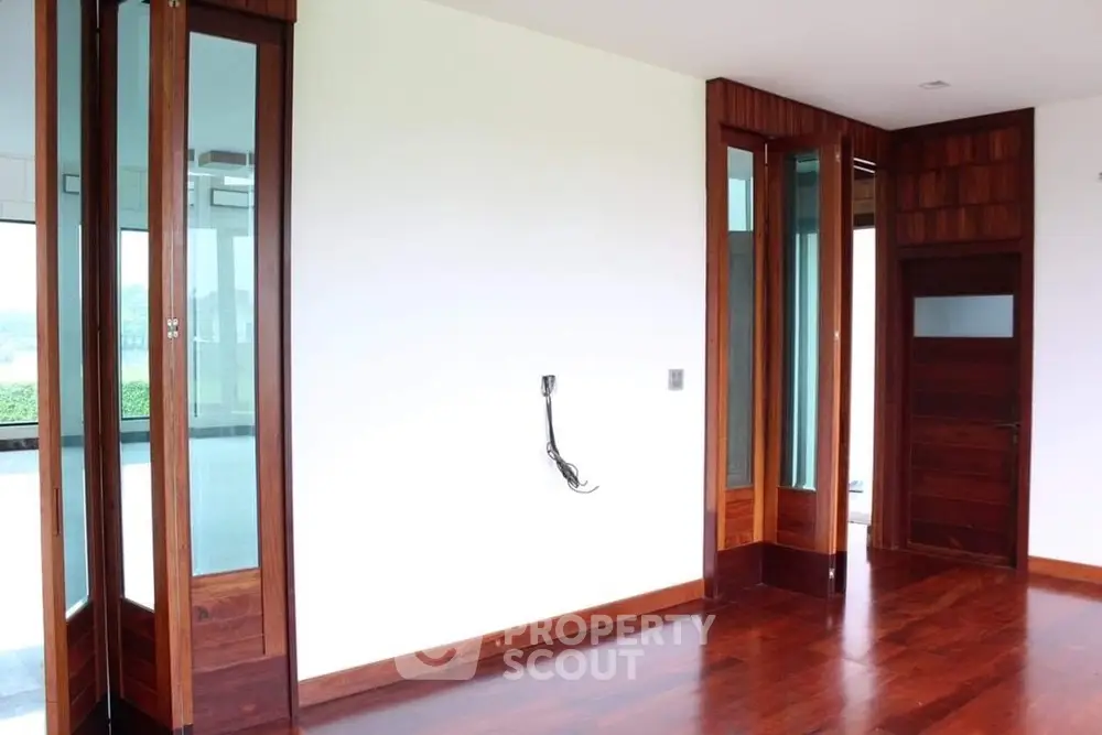 Spacious room with wooden floors and large windows, perfect for customization.