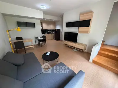 Modern living room with open kitchen, stylish furniture, and cozy ambiance in a contemporary apartment.