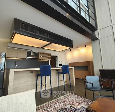 Modern open-layout kitchen with stylish bar stools and high ceiling design.