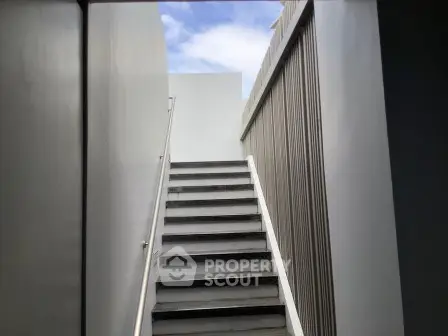 Modern architectural staircase leading to rooftop with sleek design and open sky view.