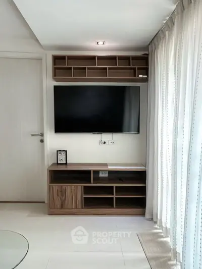 Modern living room with sleek TV unit and natural light from large window.
