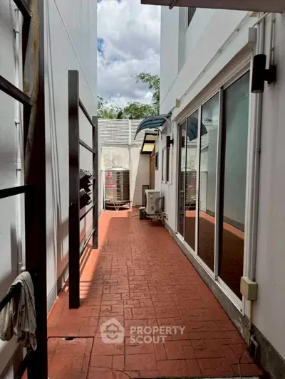 Spacious outdoor corridor with brick flooring and modern glass doors, perfect for relaxation.