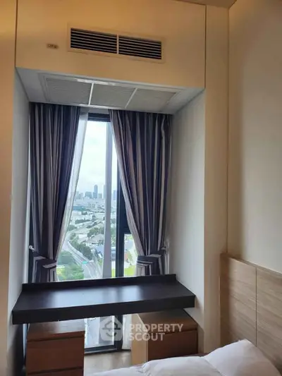 Cozy bedroom with city view, featuring a stylish desk and elegant curtains, perfect for urban living.