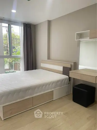 Modern bedroom with natural light, featuring a stylish bed and vanity set, perfect for urban living.