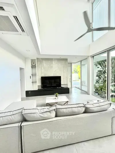 Spacious modern living room with high ceilings and large windows, featuring a sleek design and abundant natural light.